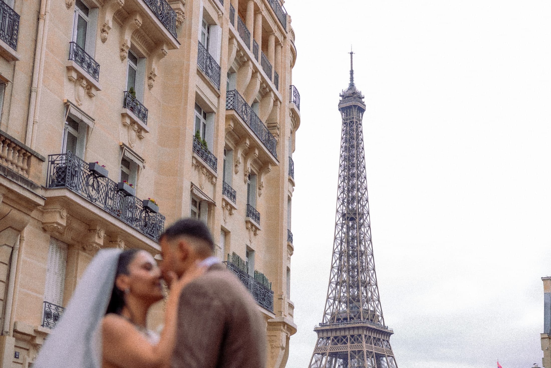 Couple de mariés s'embrassant dans une rue de Paris face à la Tour Eiffel
