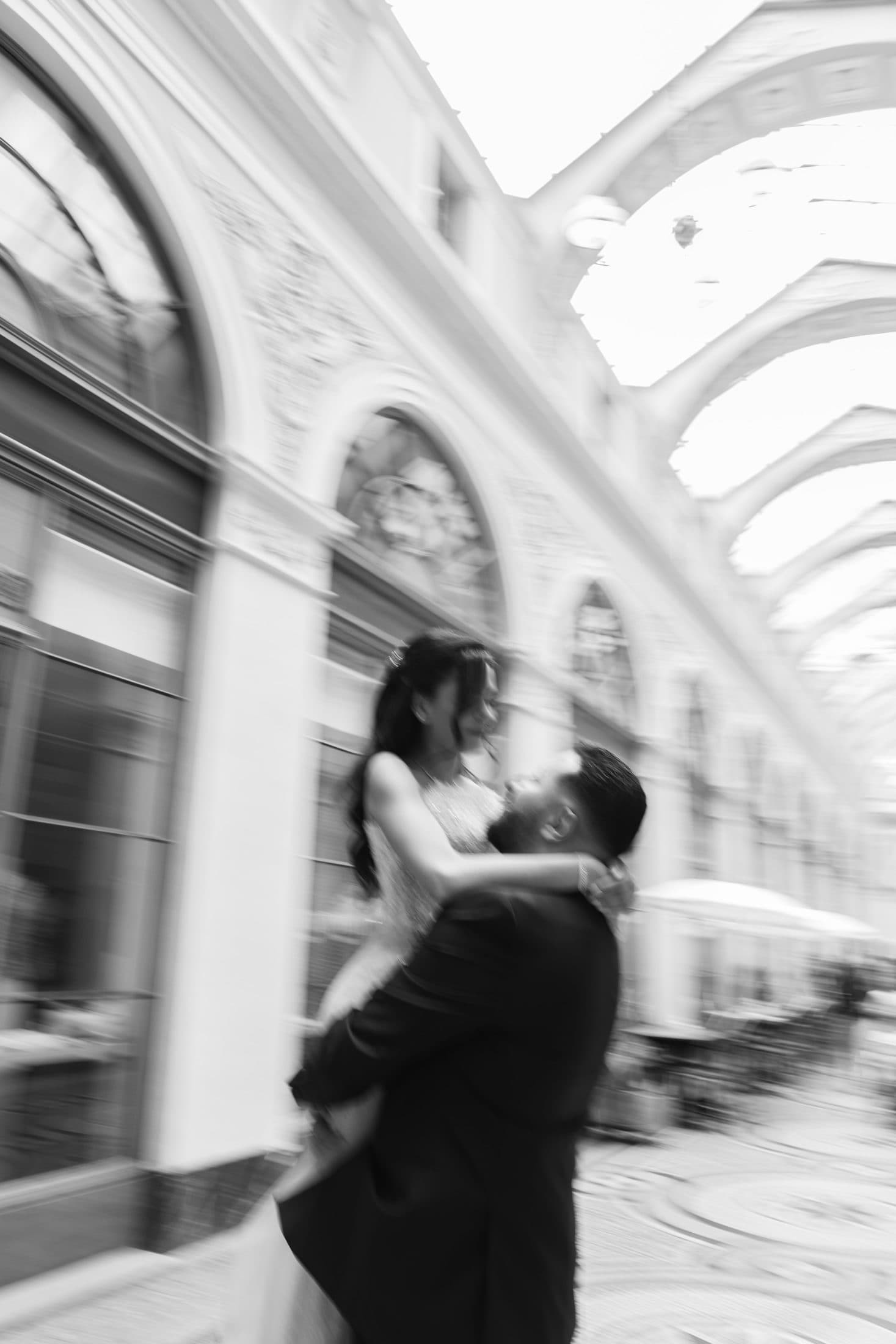 Couple de mariés tournoyant dans une galerie parisienne, effet de mouvement en noir et blanc