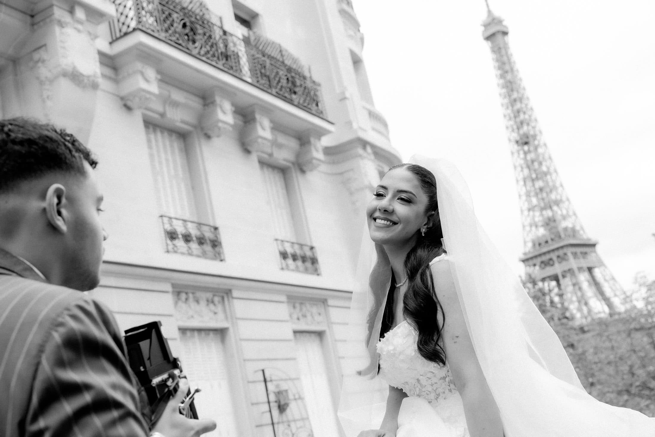 Mariée souriante filmée devant la Tour Eiffel, photo en noir et blanc