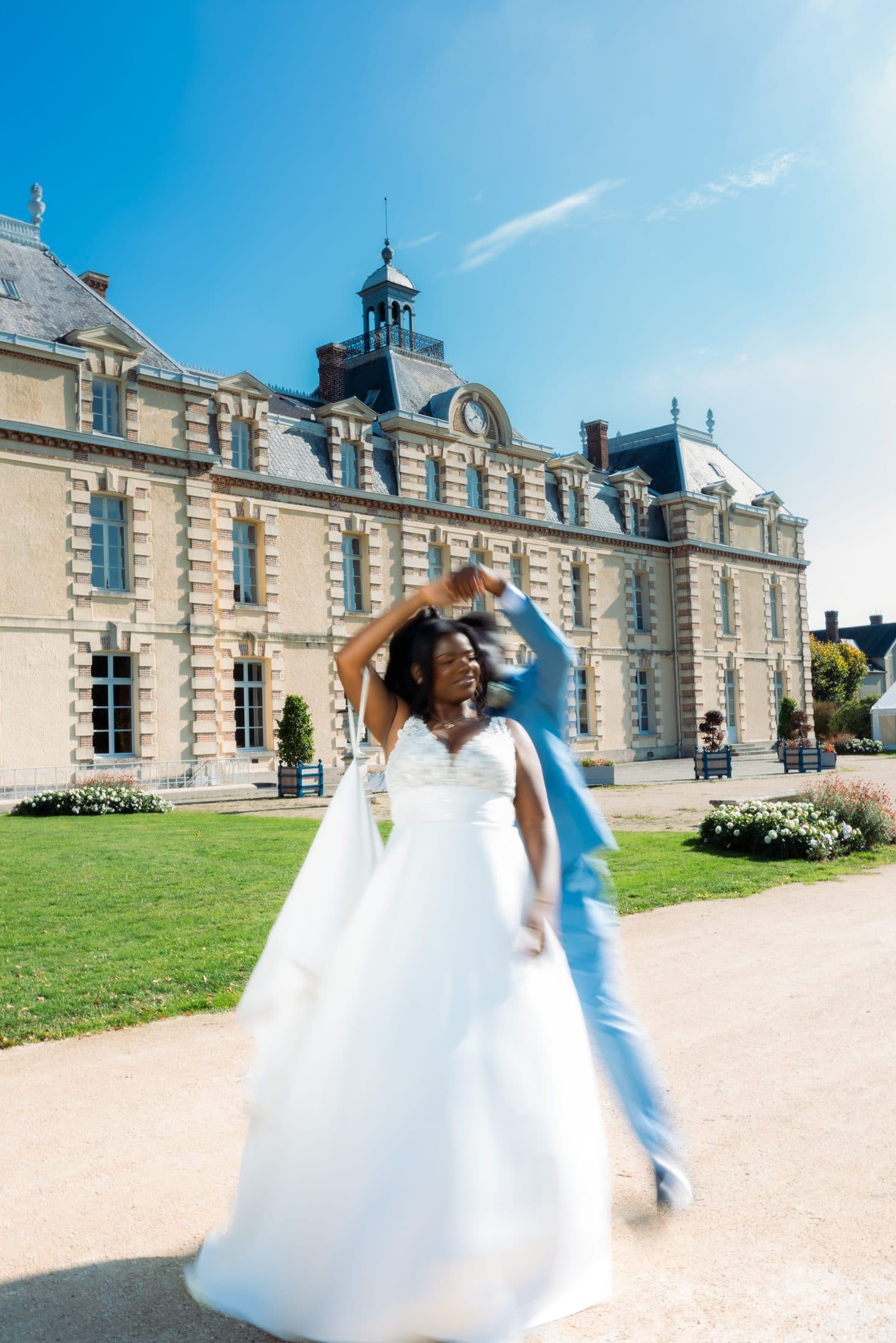 Mariée faisant tournoyer sa robe devant un château
