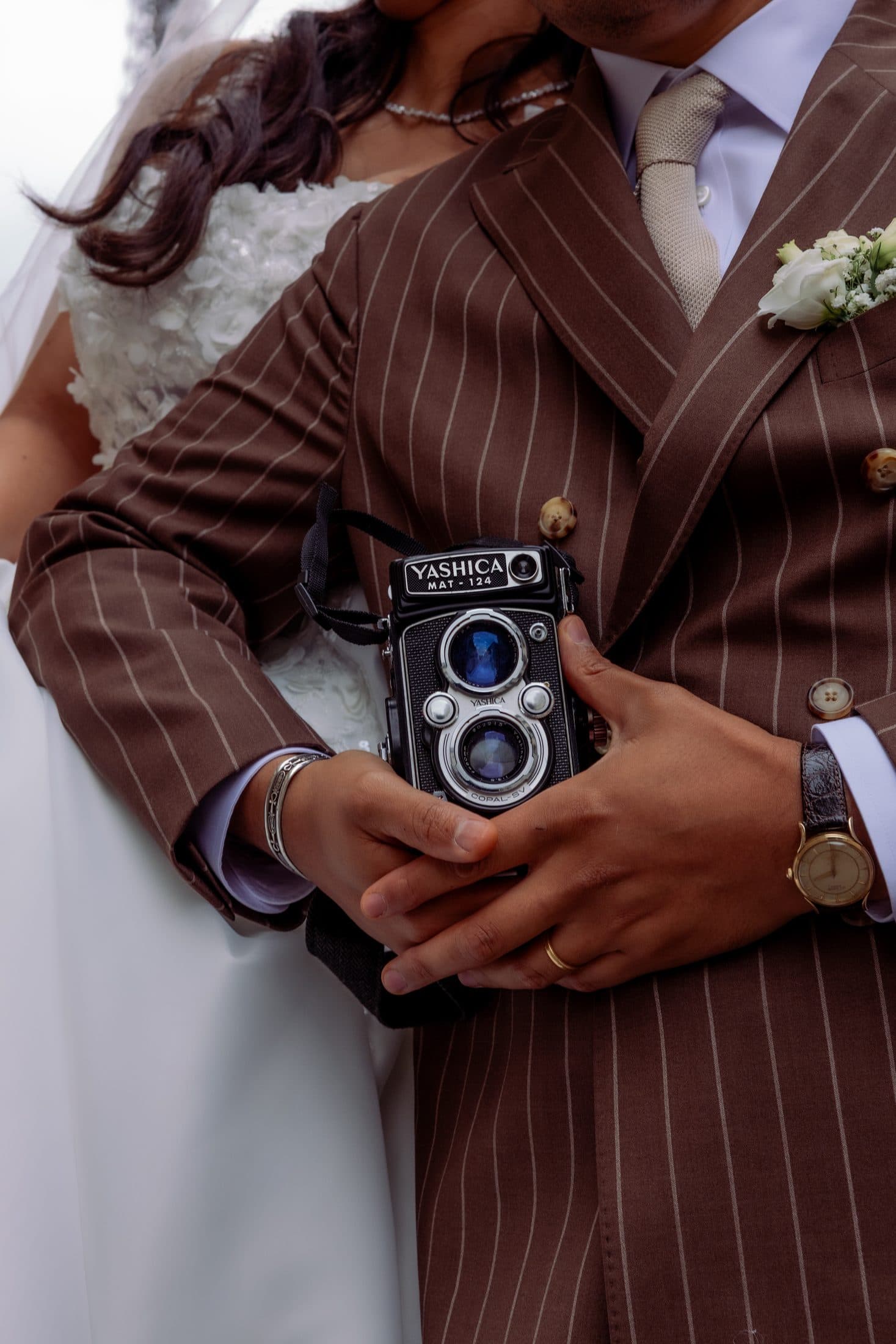 Mariés enlacés, le marié tenant un appareil photo argentique vintage
