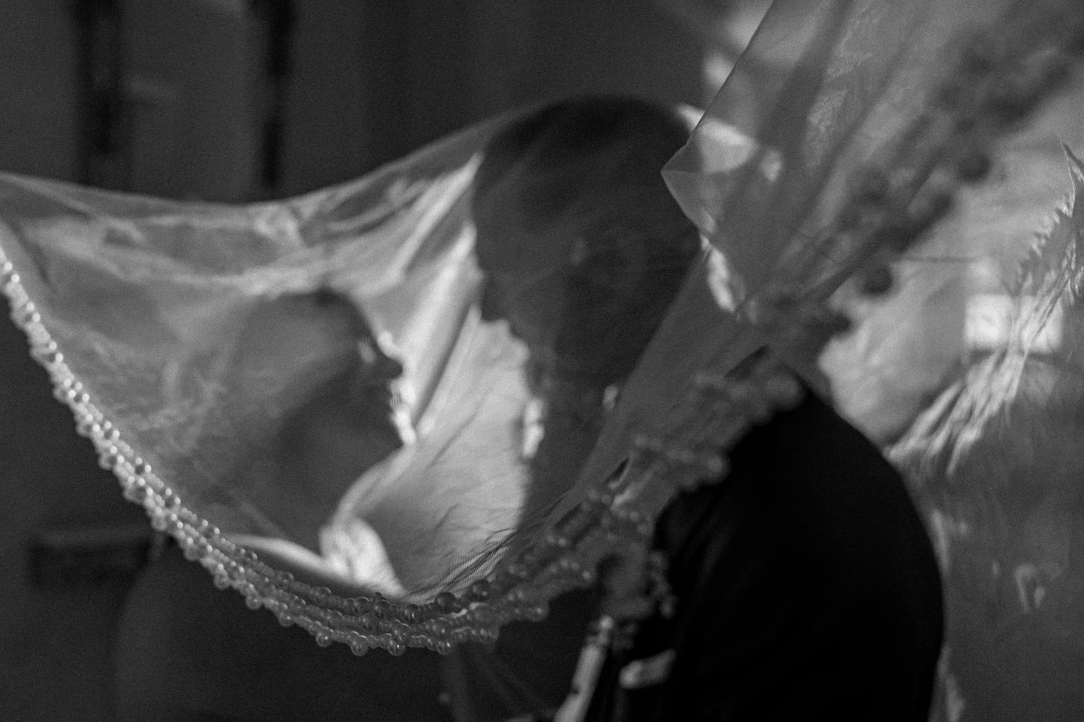 Mariés s'embrassant sous le voile, instant intime en noir et blanc